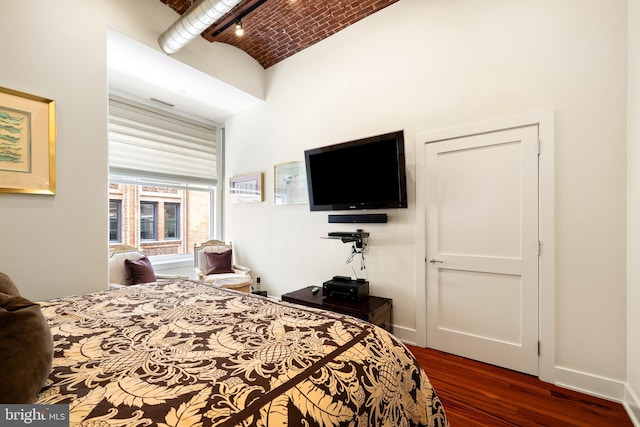 bedroom featuring brick ceiling, dark wood-style floors, visible vents, and baseboards