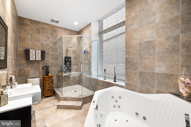 full bathroom featuring tile walls, a wealth of natural light, shower with separate bathtub, and vanity