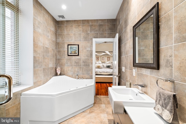 bathroom with tile patterned floors, vanity, tile walls, and a tub