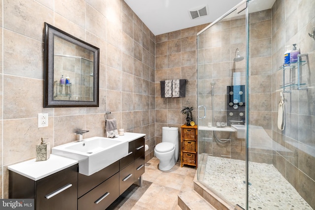 bathroom with visible vents, toilet, a stall shower, tile walls, and vanity