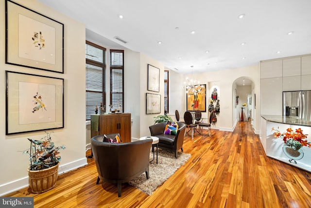 living area featuring light wood-type flooring, visible vents, recessed lighting, arched walkways, and baseboards