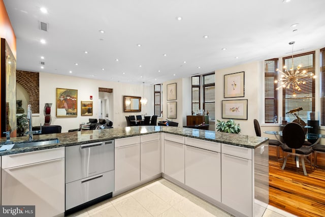 kitchen with light hardwood / wood-style flooring, white cabinets, sink, a chandelier, and dark stone counters