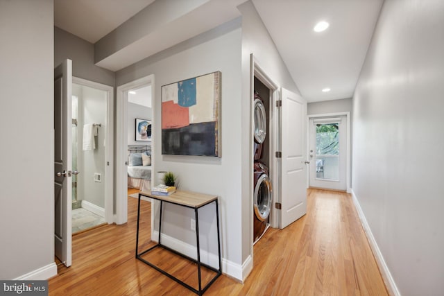 hall with light hardwood / wood-style flooring and stacked washer / dryer