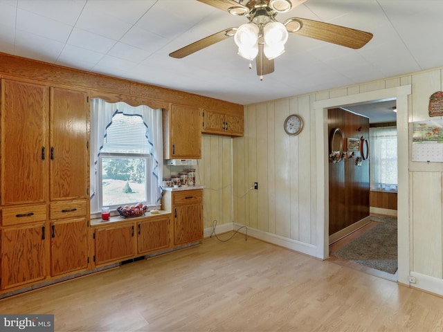 kitchen featuring wooden walls, ceiling fan, and light hardwood / wood-style floors