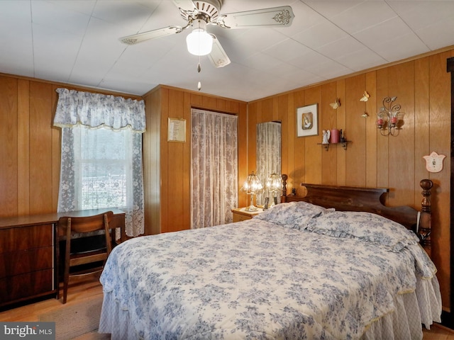 bedroom with ceiling fan, wooden walls, and hardwood / wood-style floors