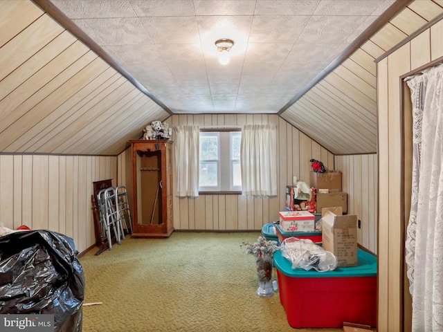 bonus room featuring lofted ceiling, wood walls, and carpet