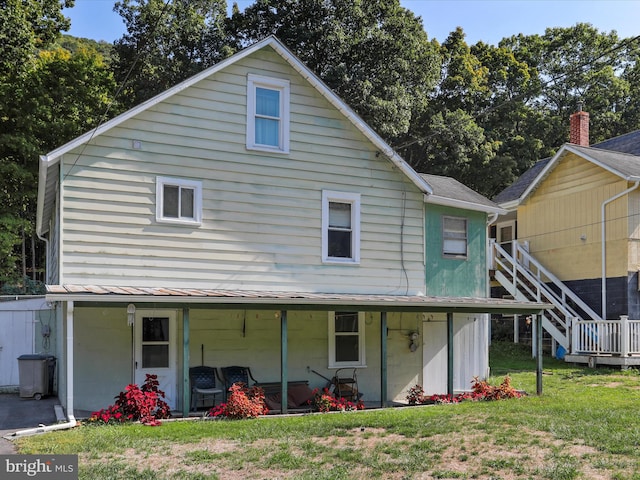 back of property with a porch and a lawn