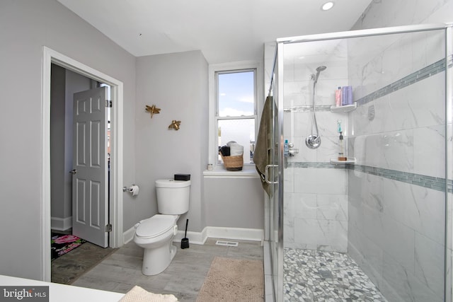 bathroom featuring a shower with door, hardwood / wood-style floors, and toilet