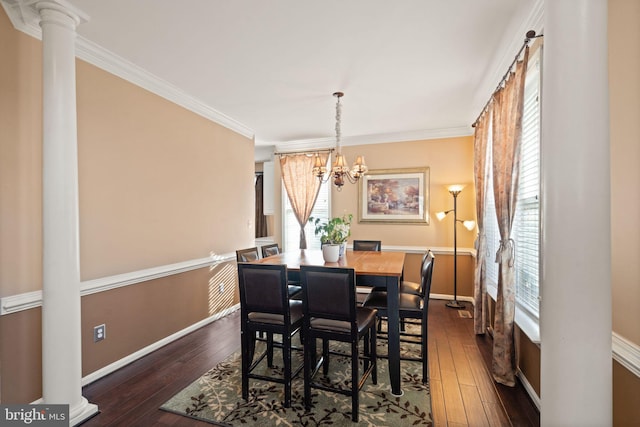 dining room featuring dark wood-type flooring, ornamental molding, an inviting chandelier, and decorative columns