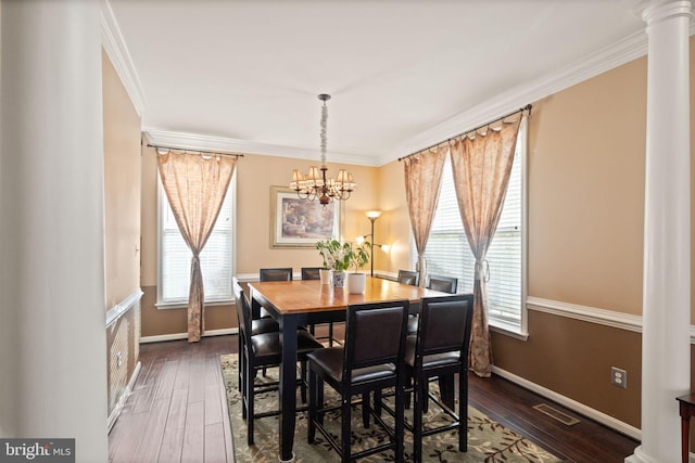 dining space featuring dark wood-type flooring, crown molding, and decorative columns