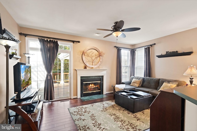 living room with dark wood-type flooring, a high end fireplace, and ceiling fan