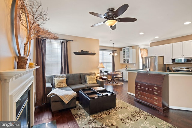 living room featuring dark wood-type flooring and ceiling fan with notable chandelier