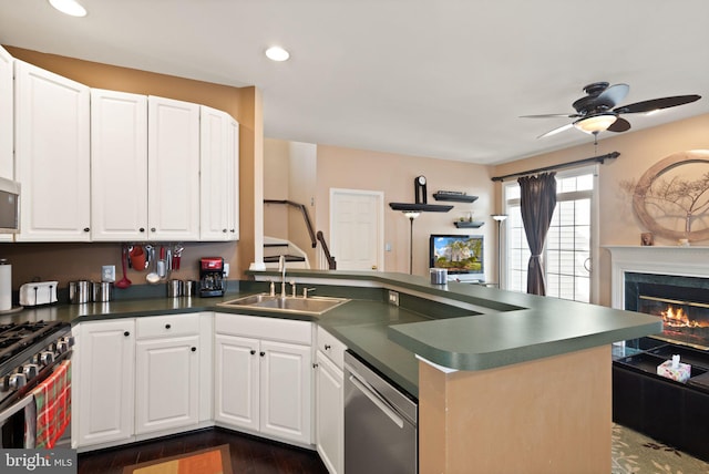 kitchen with stainless steel appliances, white cabinetry, sink, dark wood-type flooring, and kitchen peninsula