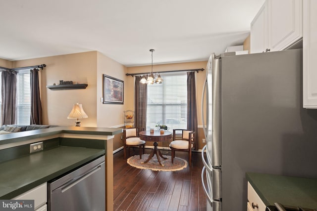 kitchen featuring white cabinetry, appliances with stainless steel finishes, dark hardwood / wood-style floors, an inviting chandelier, and hanging light fixtures