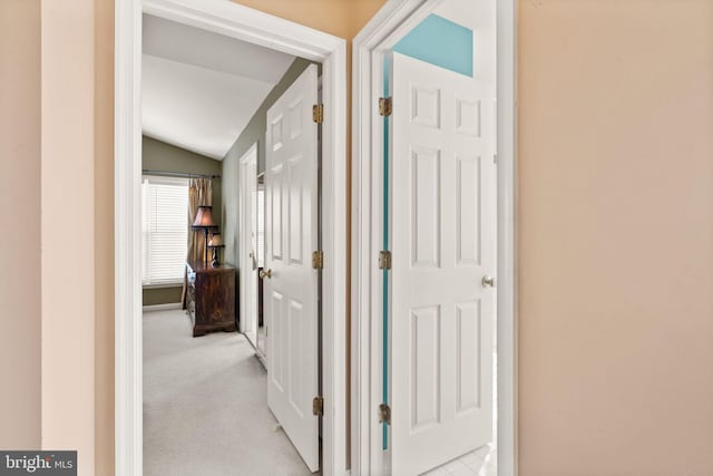 corridor with vaulted ceiling and light carpet