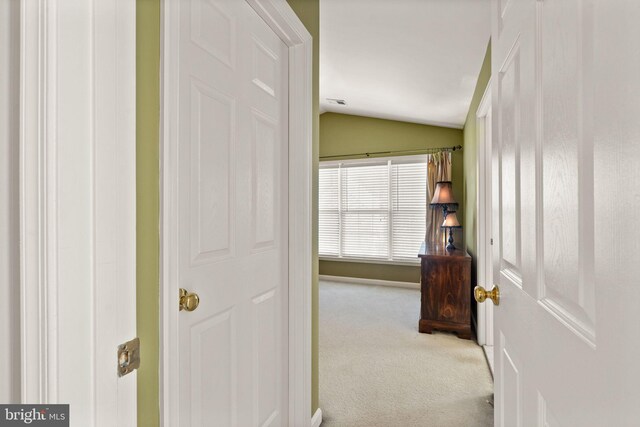 hallway featuring carpet and lofted ceiling