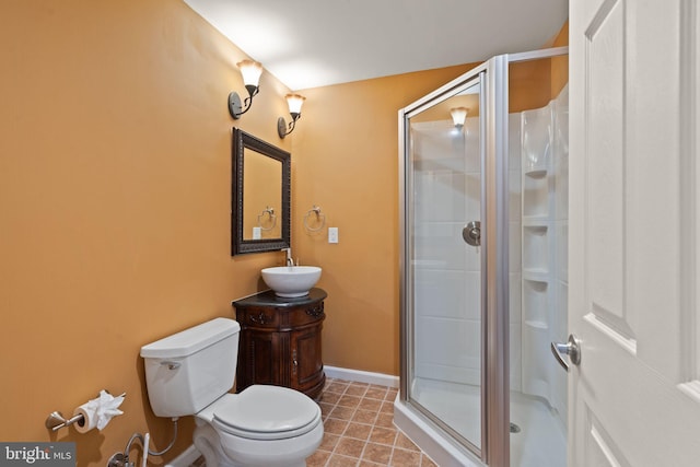 bathroom featuring toilet, vanity, tile patterned flooring, and a shower with door