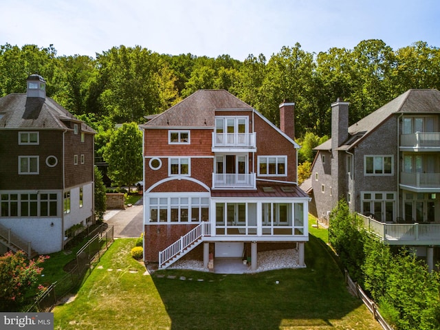 back of property with a balcony and a lawn