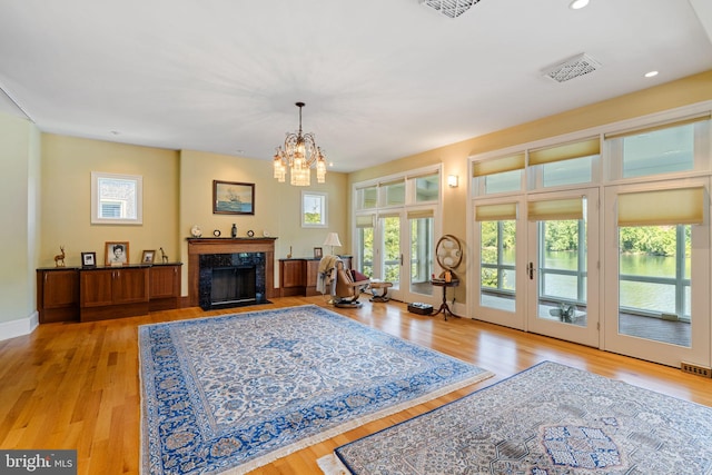 living room featuring french doors, a chandelier, a high end fireplace, and light hardwood / wood-style flooring