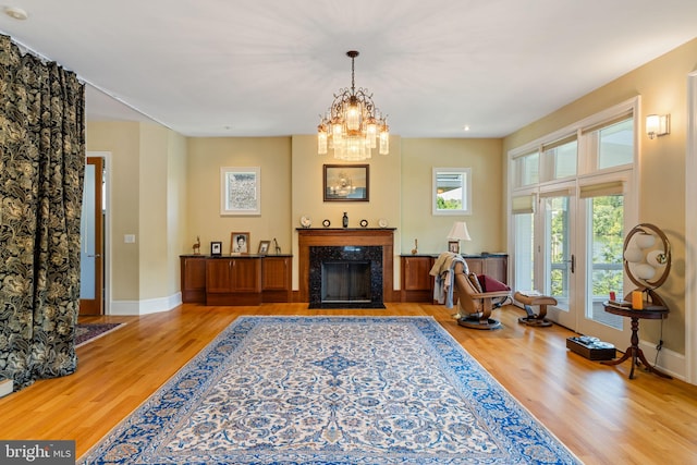 living room with a fireplace, an inviting chandelier, and light hardwood / wood-style floors