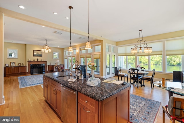 kitchen featuring dishwasher, a healthy amount of sunlight, dark stone countertops, and a fireplace