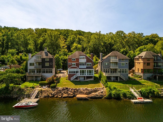 rear view of property featuring a water view, a yard, and a balcony