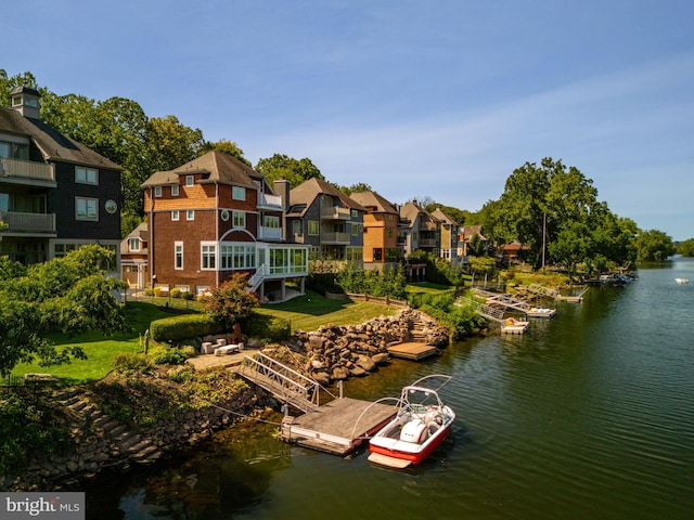 view of dock with a residential view, a water view, and a lawn