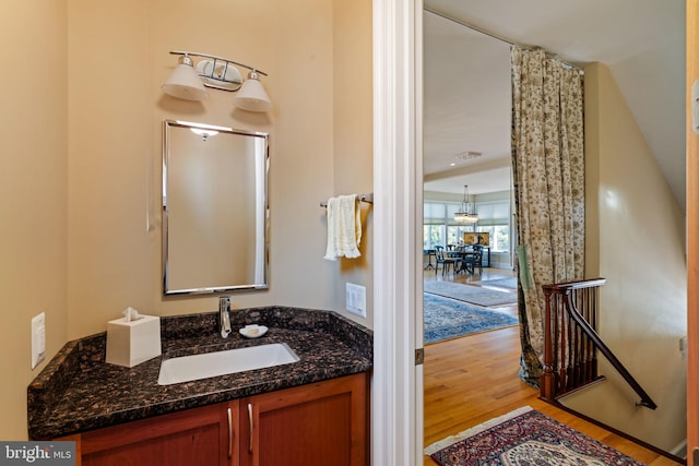 bathroom with vanity, wood-type flooring, curtained shower, and a notable chandelier