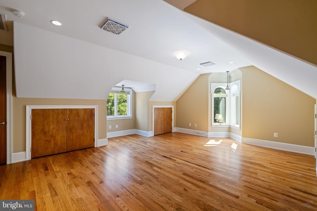 additional living space featuring lofted ceiling and light hardwood / wood-style floors