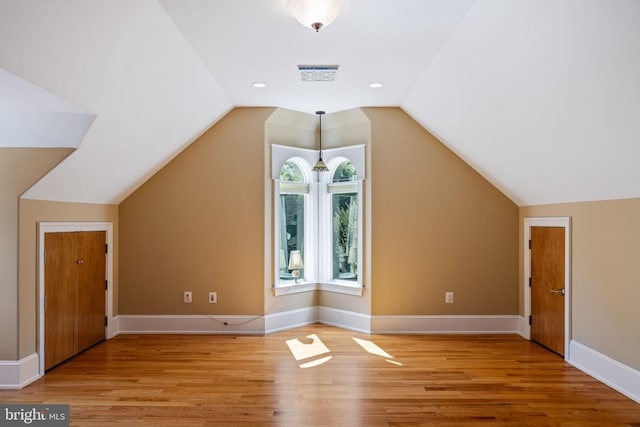 additional living space featuring lofted ceiling and light hardwood / wood-style floors