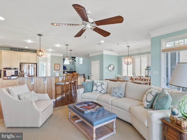 living room with ornamental molding, ceiling fan with notable chandelier, and light wood-type flooring