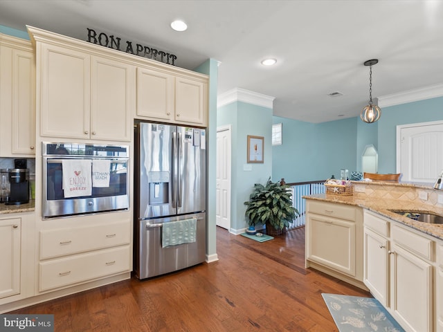 kitchen with dark hardwood / wood-style flooring, cream cabinets, hanging light fixtures, stainless steel appliances, and sink