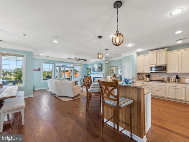 kitchen with decorative light fixtures, light stone countertops, hardwood / wood-style floors, stainless steel appliances, and ceiling fan