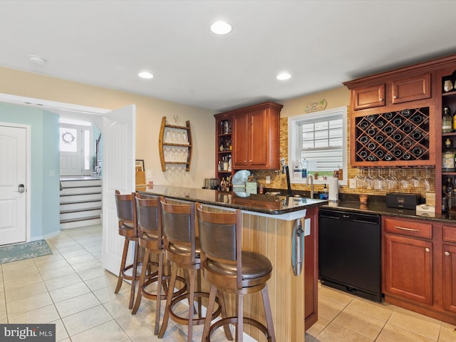 kitchen with a kitchen breakfast bar, dishwasher, plenty of natural light, and dark stone counters