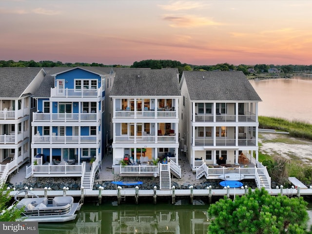 back house at dusk with a balcony and a water view