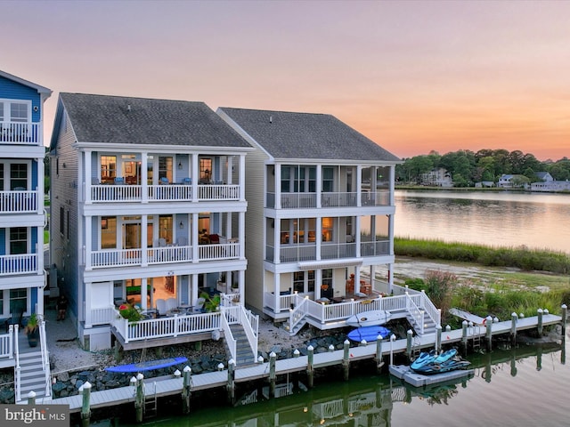 back house at dusk with a balcony and a water view