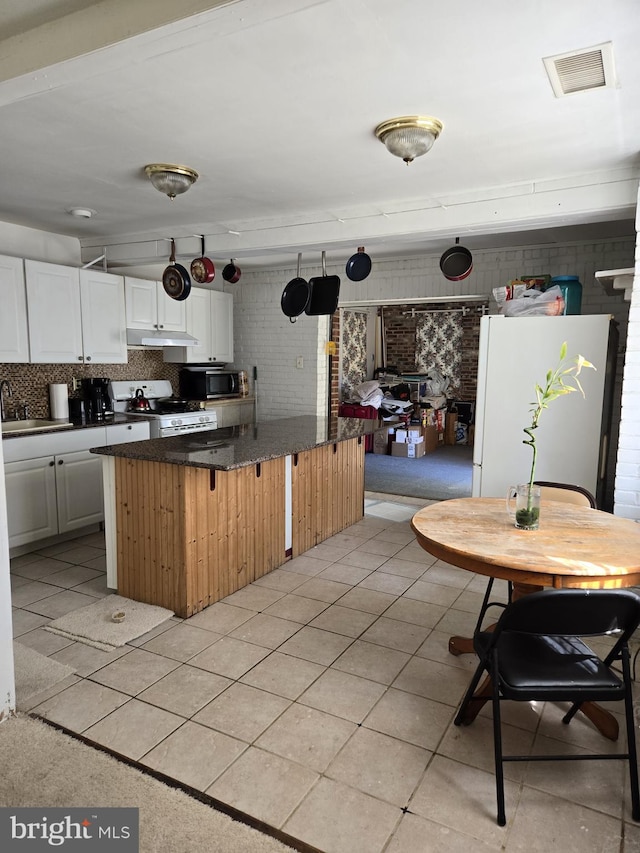 kitchen featuring white cabinetry, light tile patterned flooring, white appliances, and backsplash