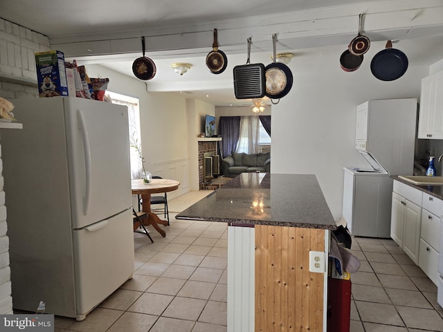 kitchen featuring a kitchen bar, a fireplace, a center island, white cabinets, and white refrigerator