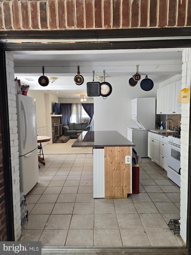 kitchen featuring a breakfast bar area, white appliances, a kitchen island, white cabinets, and decorative backsplash