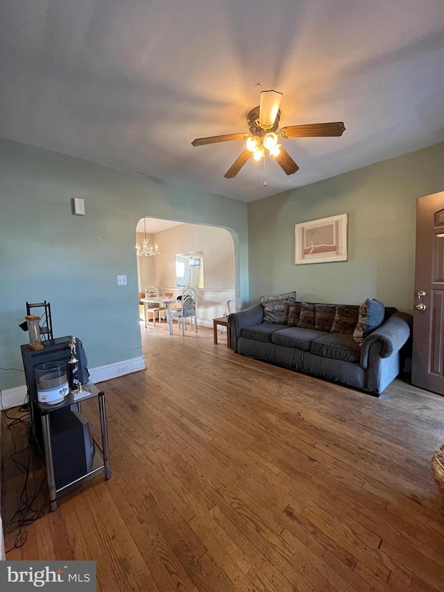 living room with ceiling fan with notable chandelier and hardwood / wood-style floors