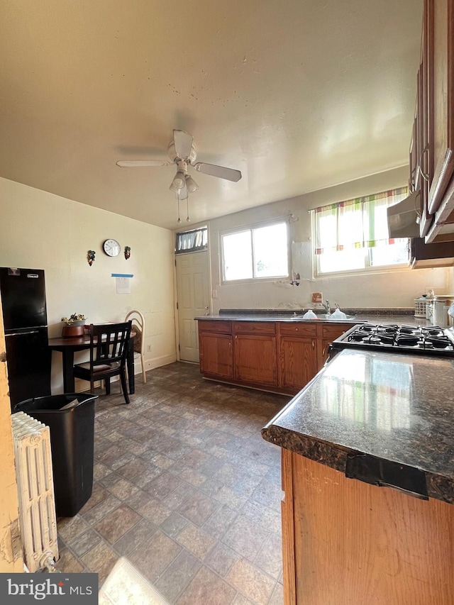 kitchen featuring range, sink, ceiling fan, and black refrigerator