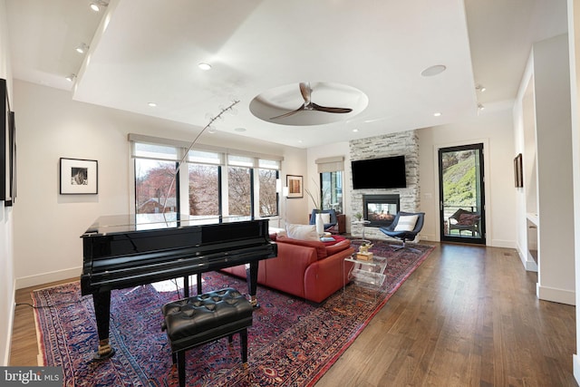 living area with a fireplace, wood finished floors, and a healthy amount of sunlight