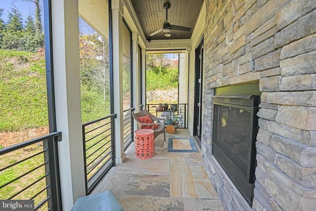 unfurnished sunroom with an outdoor stone fireplace