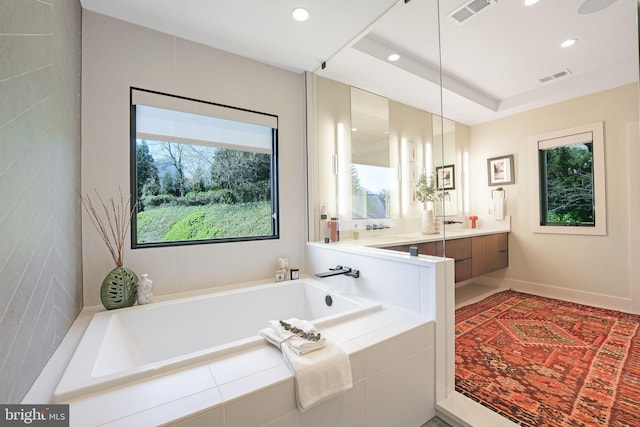 bathroom with vanity, a healthy amount of sunlight, and tiled bath