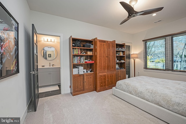 bedroom with visible vents, light carpet, a ceiling fan, ensuite bathroom, and baseboards