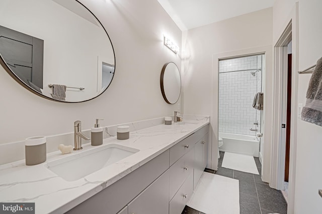 full bathroom featuring washtub / shower combination, double vanity, a sink, tile patterned floors, and toilet