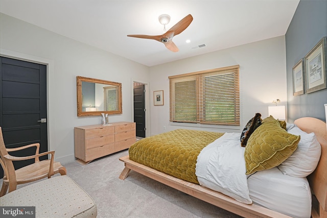 bedroom with ceiling fan, light colored carpet, visible vents, and baseboards