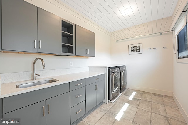 washroom featuring a sink, cabinet space, baseboards, wood ceiling, and washing machine and clothes dryer