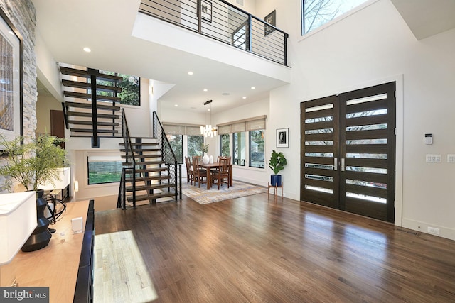 entryway featuring french doors, hardwood / wood-style floors, a high ceiling, and an inviting chandelier