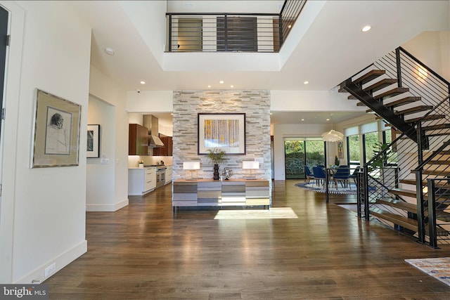 foyer entrance with stairway, wood finished floors, baseboards, recessed lighting, and a towering ceiling